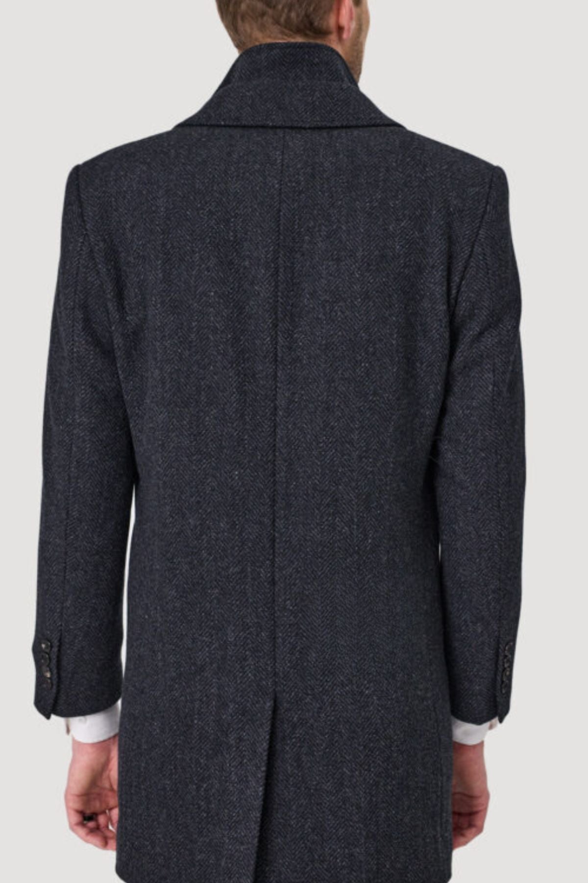 A man is seen from behind wearing a dark, textured Savile Row Jared Removable Collar Coat with a back vent and buttoned cuffs. The coat’s collar is visible, his hands rest at his sides, and the background is a plain light gray.