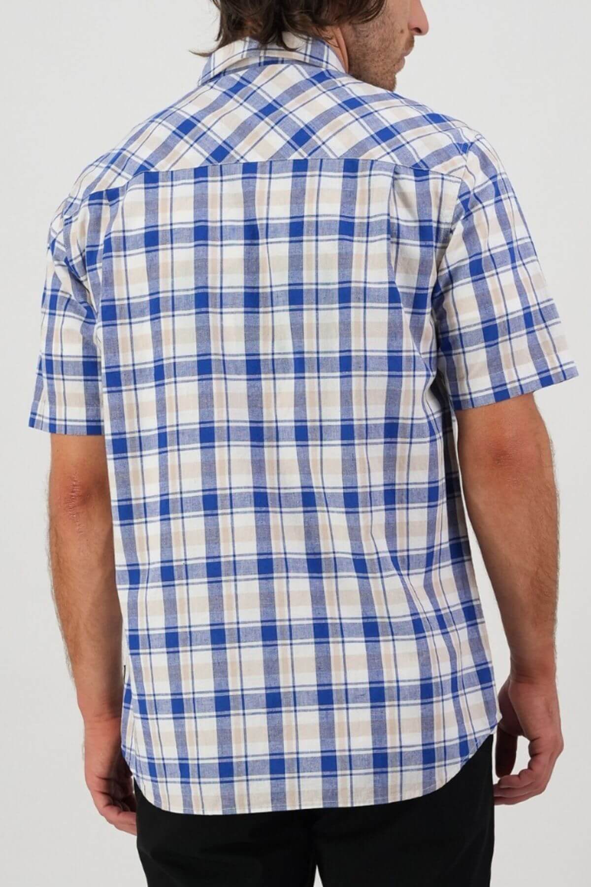 A person with dark hair, wearing a Swanndri Coleridge Short Sleeve Shirt in blue and white plaid, is shown from the back with dark pants. The plain, light background accentuates the shirt's classic fit style.