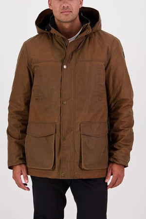A man stands against a plain white background wearing the Swanndri Evans Flat v2 Oilskin Jacket, a brown waxed cotton hooded coat with front buttons and large flap pockets.