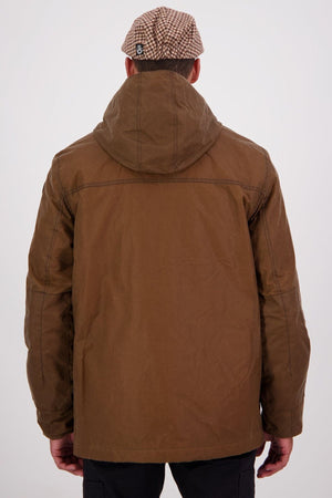 A person is seen from behind wearing the Swanndri Evans Flat v2 Oilskin Jacket and a brown-and-white checkered cap against a plain, light background.