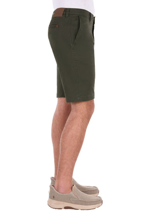 A person wearing Thomas Cook Harrison Short in olive green vintage wash, paired with a white shirt and beige slip-on shoes, shown from the side against a plain white background.