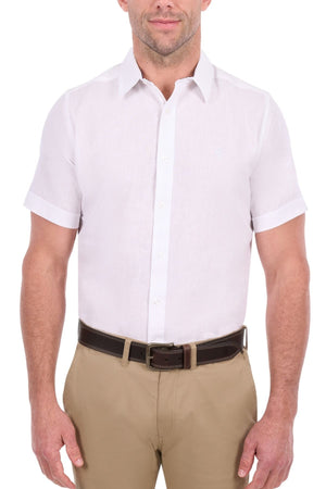 A man wearing the Thomas Cook Linen Short Sleeve Shirt, neatly tucked into beige pants with a dark brown belt, stands against a plain white background.
