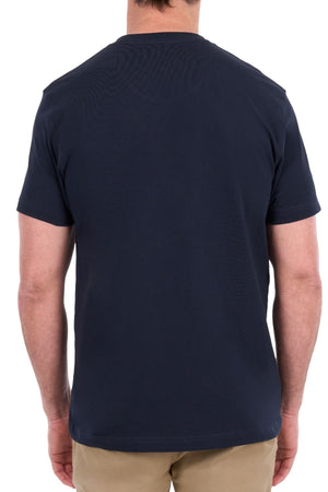 A person is standing with their back to the camera, wearing a Thomas Cook Nathan Tee in plain navy blue, made from 100% cotton, paired with beige pants against a white background.