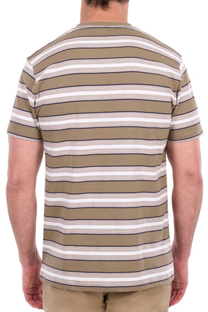 A person is seen from the back wearing the Thomas Cook Nick Tee, a short-sleeve shirt featuring tan, white, and gray horizontal classic stripes made from soft cotton jersey. They are also wearing tan pants.