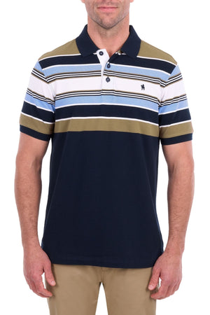 A man is wearing the Thomas Cook Phillip Polo, a short-sleeve cotton pique shirt with multi-colour stripes in blue, white, olive, and navy. The polo features a collar, three-button placket, and a small embroidered logo on the left chest. It is paired with tan pants.