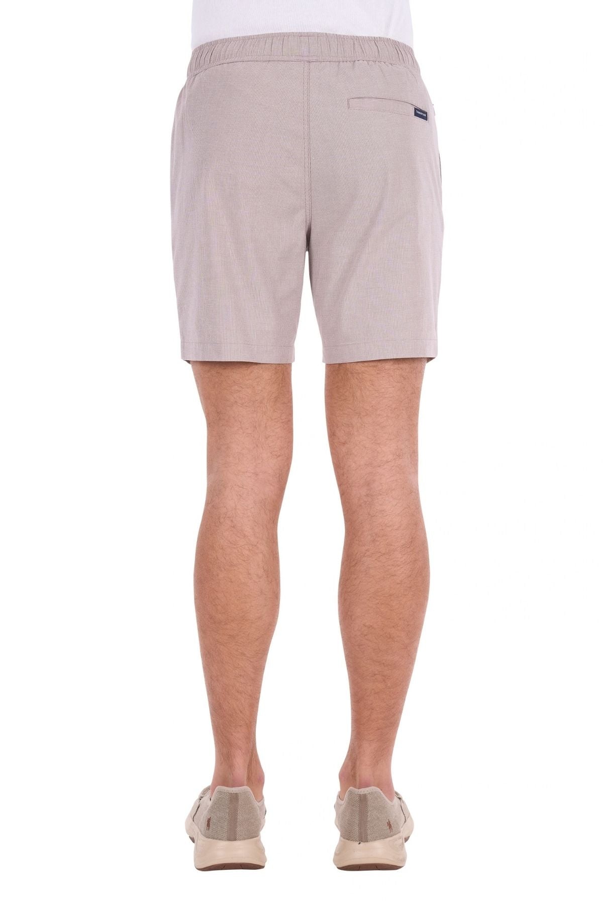 A person is shown from the back against a white background, wearing light beige Thomas Cook Rowan Shorts crafted from premium textured fabric and paired with beige shoes.