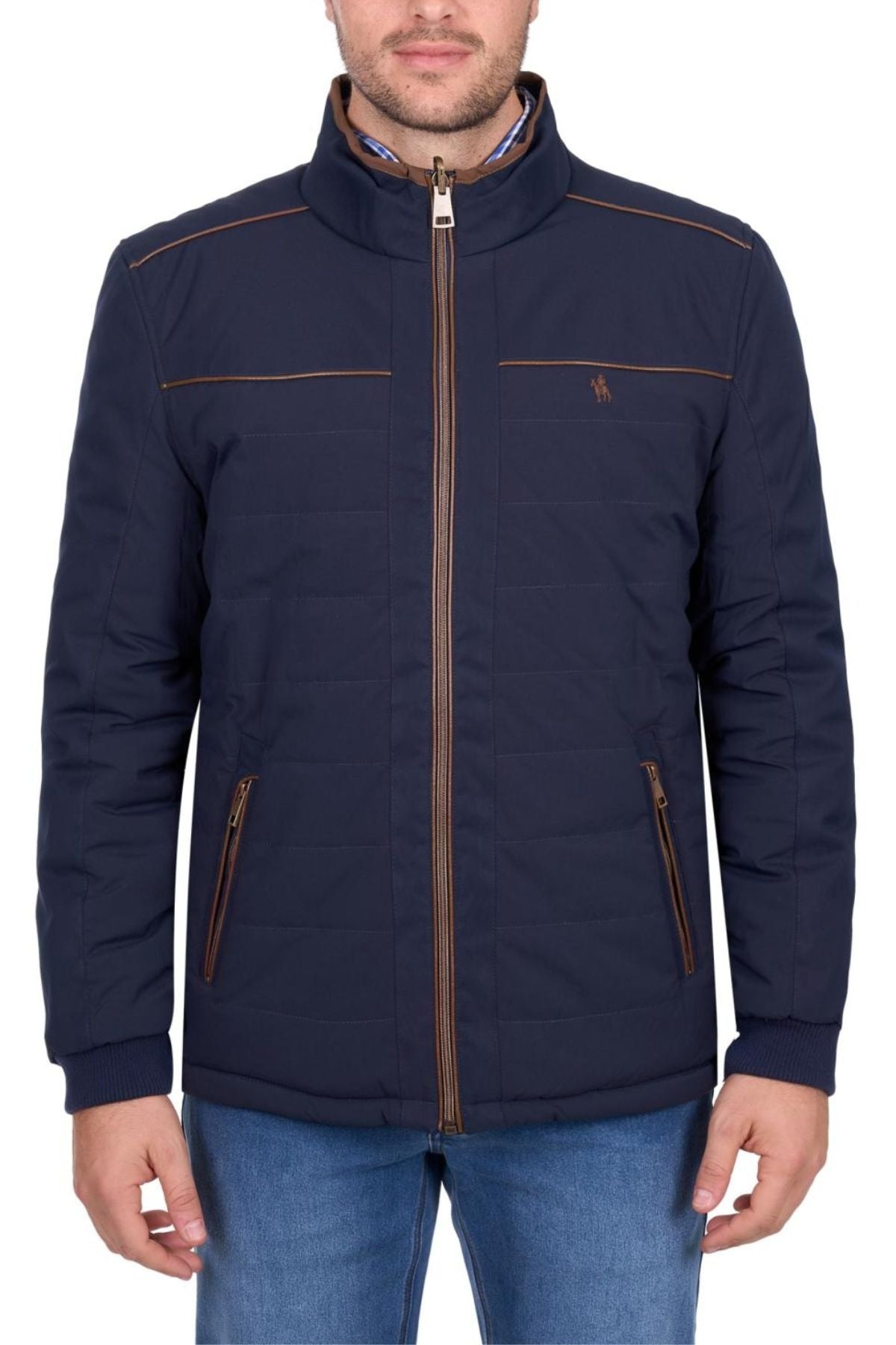 A man is wearing a navy blue Thomas Cook Toby Reversible Jacket with brown zippers, a small chest logo, high collar, two zippered pockets, and paired with blue jeans. The quilted jacket offers both style and comfort.
