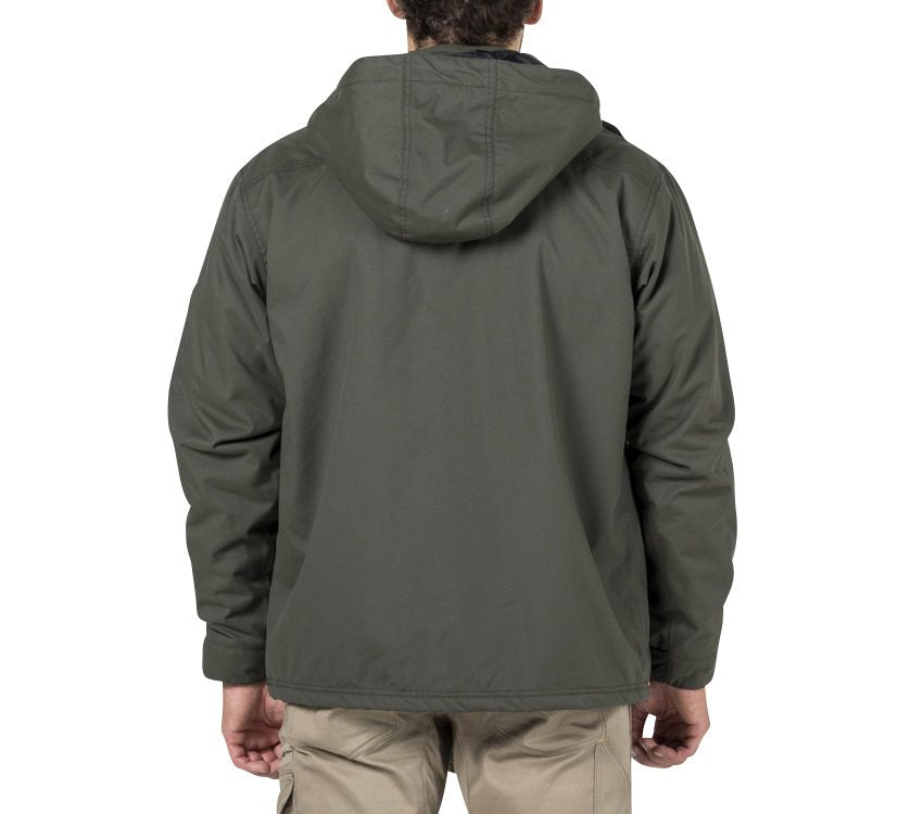 A person is shown from the back, standing against a plain white background, wearing the CAT Chinook Waterproof Jacket in dark green with an adjustable hood and khaki pants.