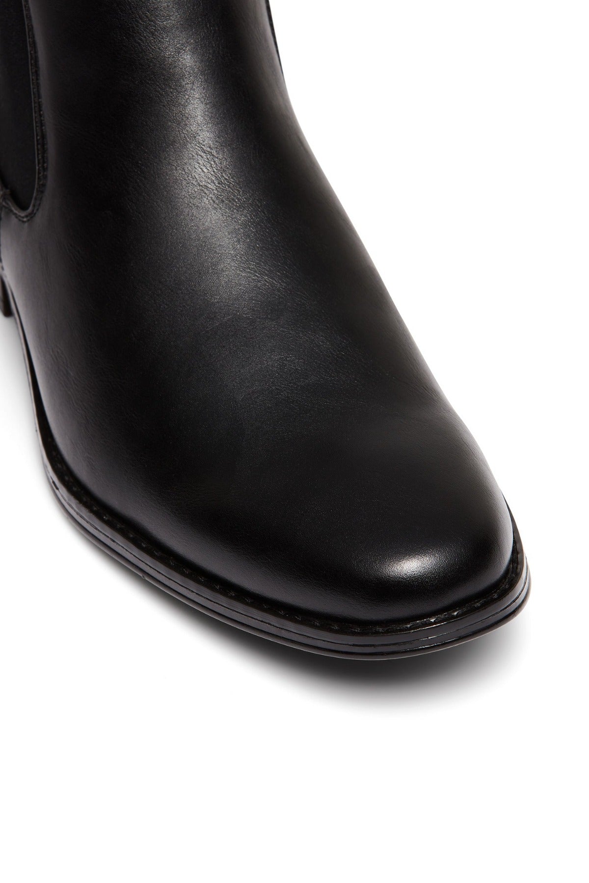 Close-up of the UNcut Canterbury Boot's toe and upper, showcasing smooth black leather, detailed stitching along the sole, and signature side gussets against a white background.