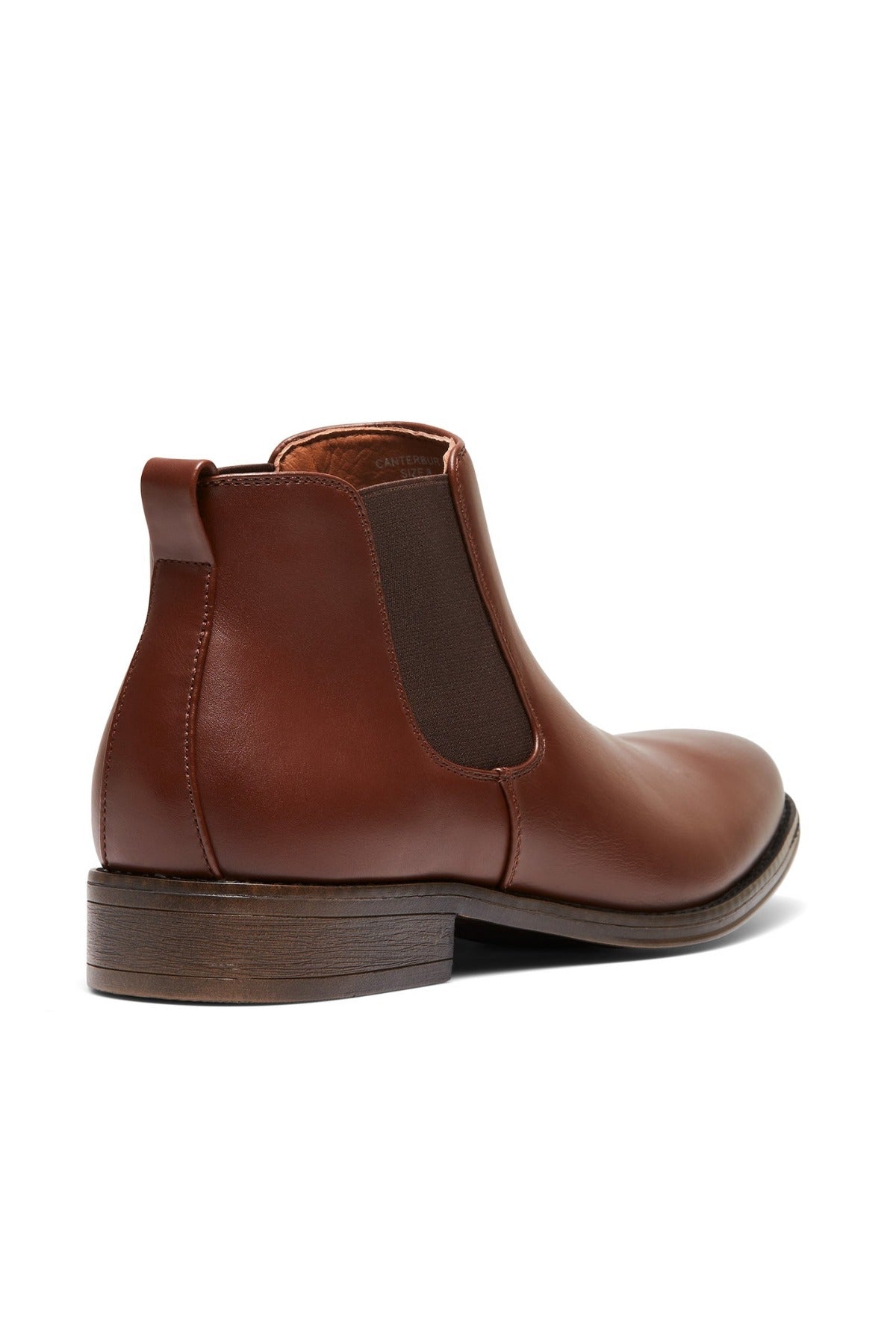 The UNcut Canterbury Boot is a brown Chelsea boot with side gussets and a pull tab at the back, featuring a sleek leather finish and a dark wooden sole. Presented at an angle, it beautifully showcases the side and back design.