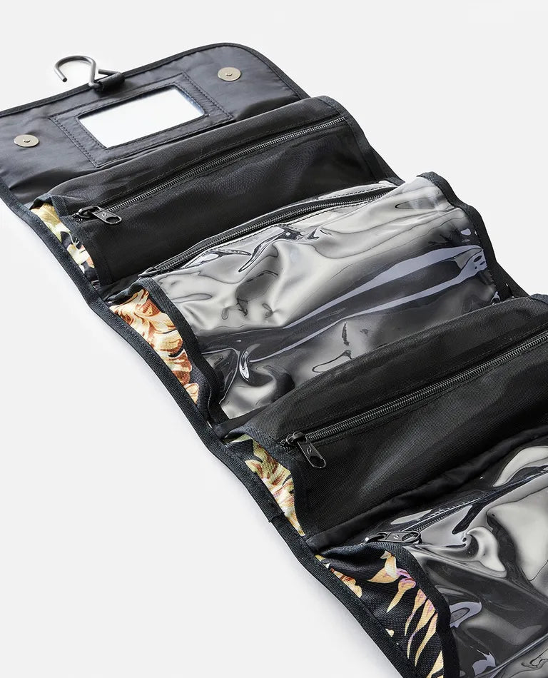 The Rip Curl Rolled Beauty Sunday Swell is a sleek black toiletry bag featuring multiple zippered compartments made from transparent plastic and fabric. It includes waterproof pockets, a sturdy metal hook for hanging, and a small rectangular mirror on the top flap.