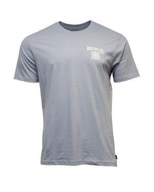 The Rip Curl Cosmic Burst Tee is a light blue, 100% cotton T-shirt featuring "Rip Curl Co" and a white graphic on the left chest, short sleeves, and a classic crew neck. Displayed against a white background.