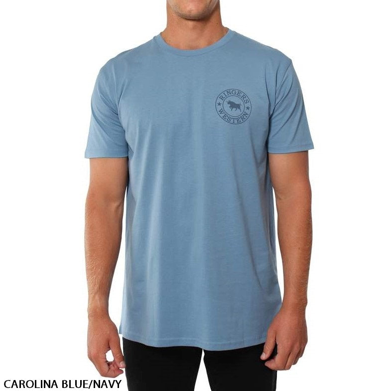 A person is wearing a Carolina Blue/Navy Ringers Western Signature Bull Original Fit T-Shirt, featuring a small circular penguin logo on the left side of the chest. The individual is standing against a plain white background, paired with black pants.