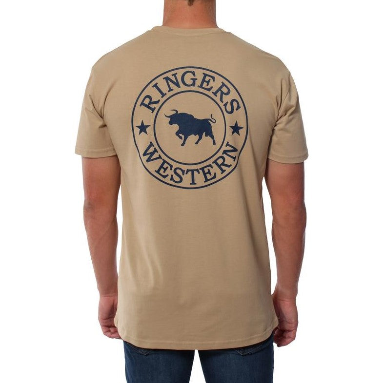 A person is wearing the Ringers Western Signature Bull Original Fit T-Shirt in beige, crafted from 100% cotton. The comfortable T-shirt features a large circular logo in navy blue on the back, showcasing a bull in the center, surrounded by the text "Ringers Western" and stars. The person is facing away, highlighting the detailed design on the back of the T-shirt.