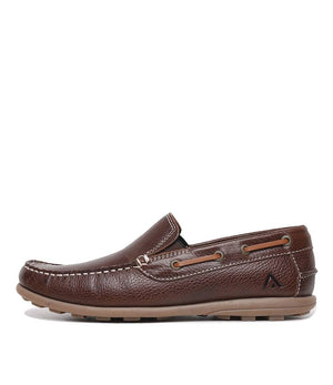 The Colorado Rocana Leather Slip On is a brown moccasin with a textured surface, visible stitching, and a tan rubber sole. It includes decorative lace holes and a subtle logo on the side. The shoe is shown in side profile on a white background, embodying Colorado style.