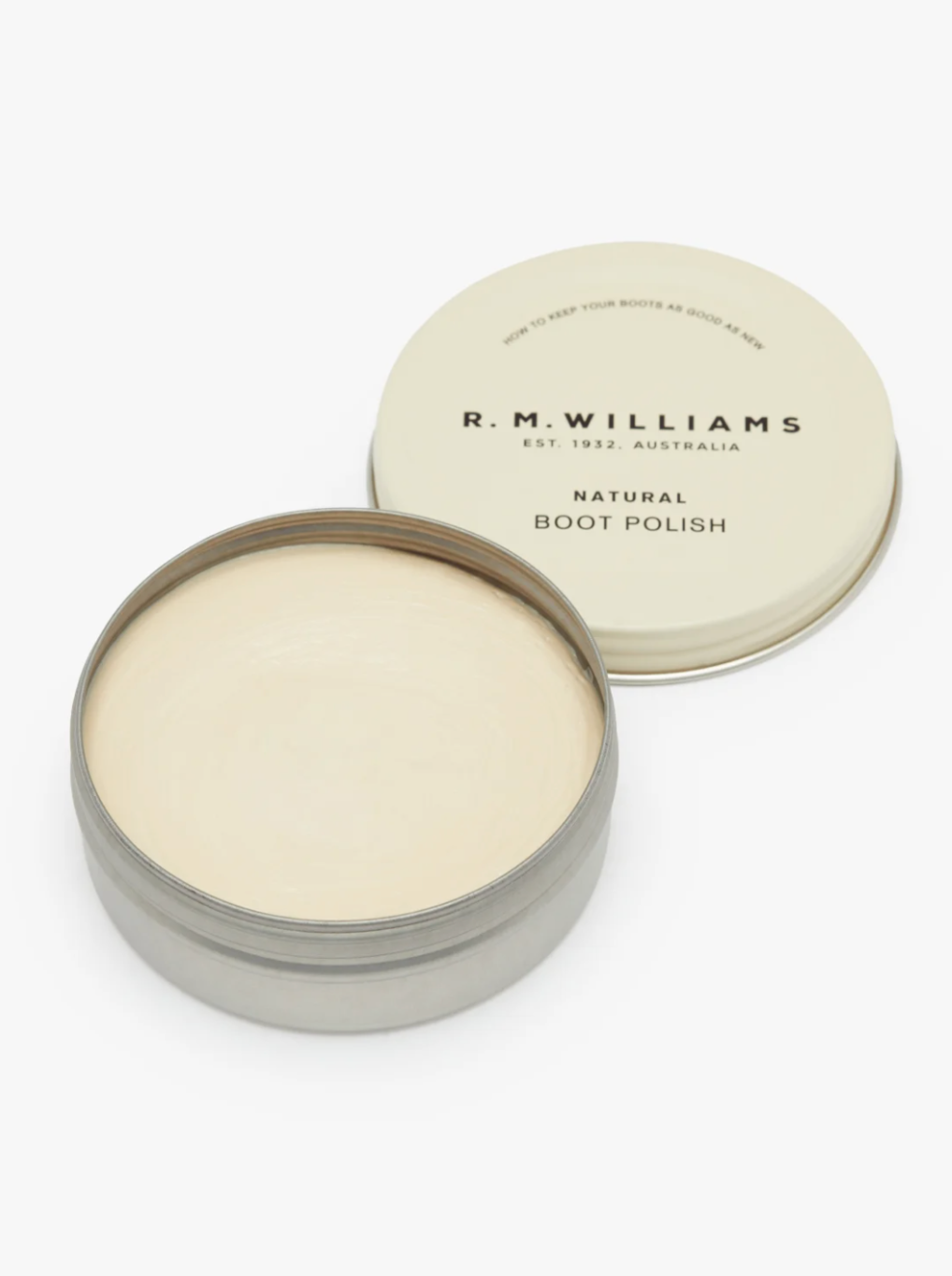 A metal tin of RM Williams Stockmans Boot Polish with the lid placed beside it. The beige lid features black text that reads "R.M. Williams Est. 1932 Australia" and "Natural Boot Polish." Inside the tin, the alcohol-free formula is cream-colored, crafted to restore color and shine to your boots.