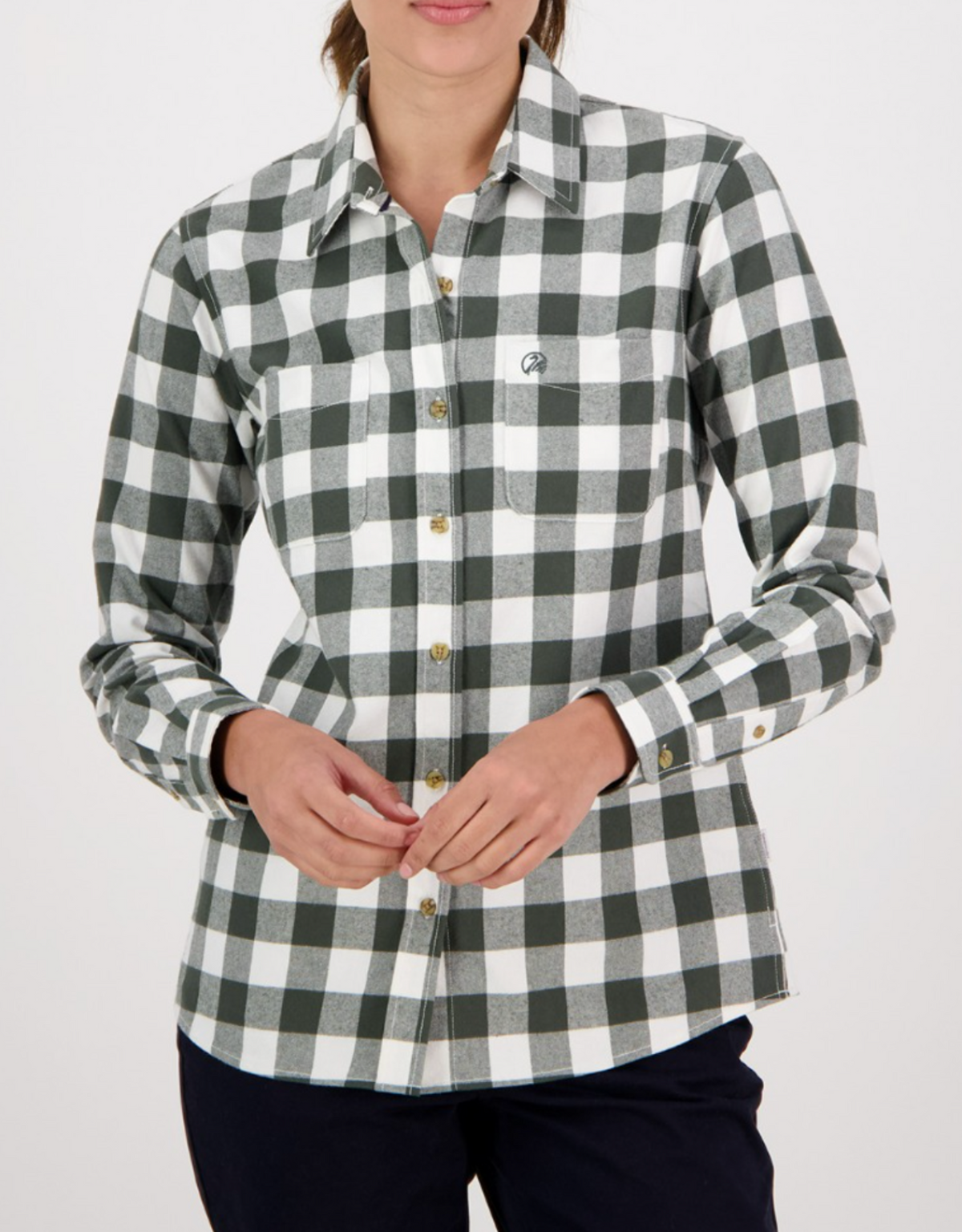 A person wears the Swanndri Womens Taranaki Tailor Shirt, a stylish black and white checkered 100% cotton button-up with long sleeves, paired with black pants, against a plain white background.