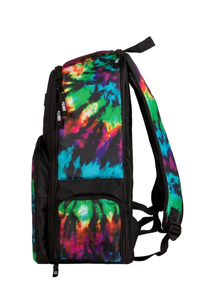 A side view of the UNIT Toxin Backpack showcases a vibrant tie-dye pattern in blue, green, yellow, pink, and purple with black straps, a zipper, several pockets, and a padded laptop compartment.