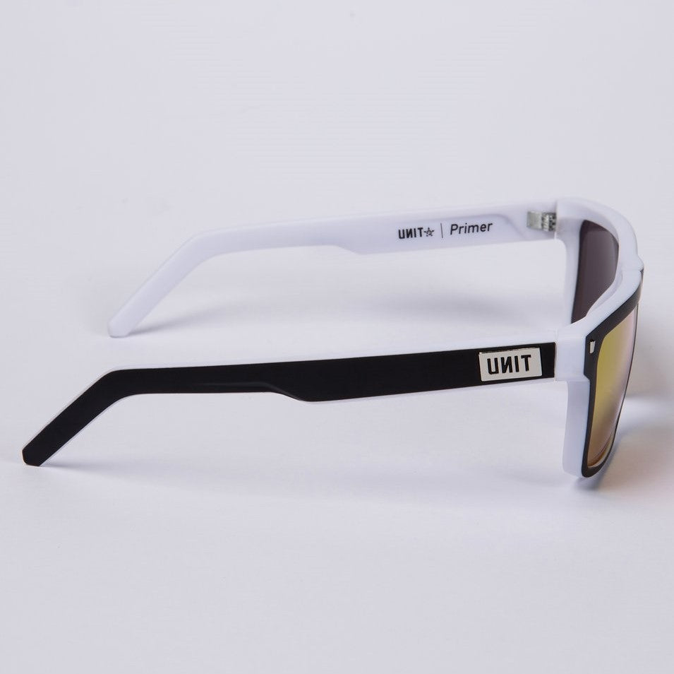 Side view of the UNIT Primer Polarised Eyewear showcasing its sleek, lightweight white and black frame with mirrored lenses. The arm proudly features the branding "UNIT" and "Primer." These stylish shades offer exceptional UV protection and stand out against a plain white background.