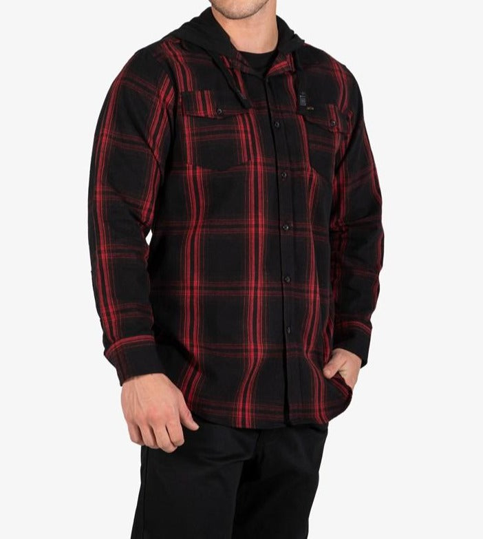 A man wearing the UNIT Chester Hood Flannel Shirt with black pants stands with one hand in his pocket against a plain white background.
