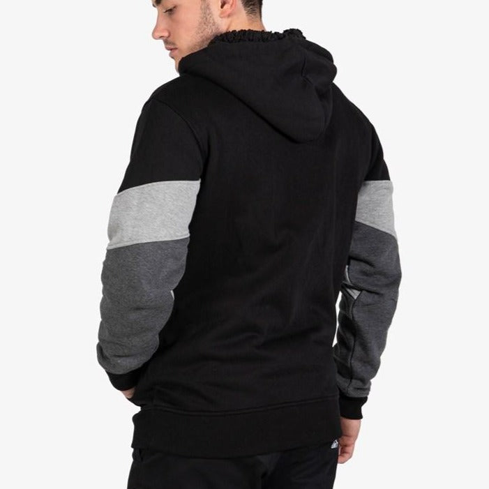 A man is shown from the back wearing the UNIT Graded Fleece Hoodie, which features color-blocked black, gray, and dark gray sleeves and a sherpa-lined hood, against a plain white background.