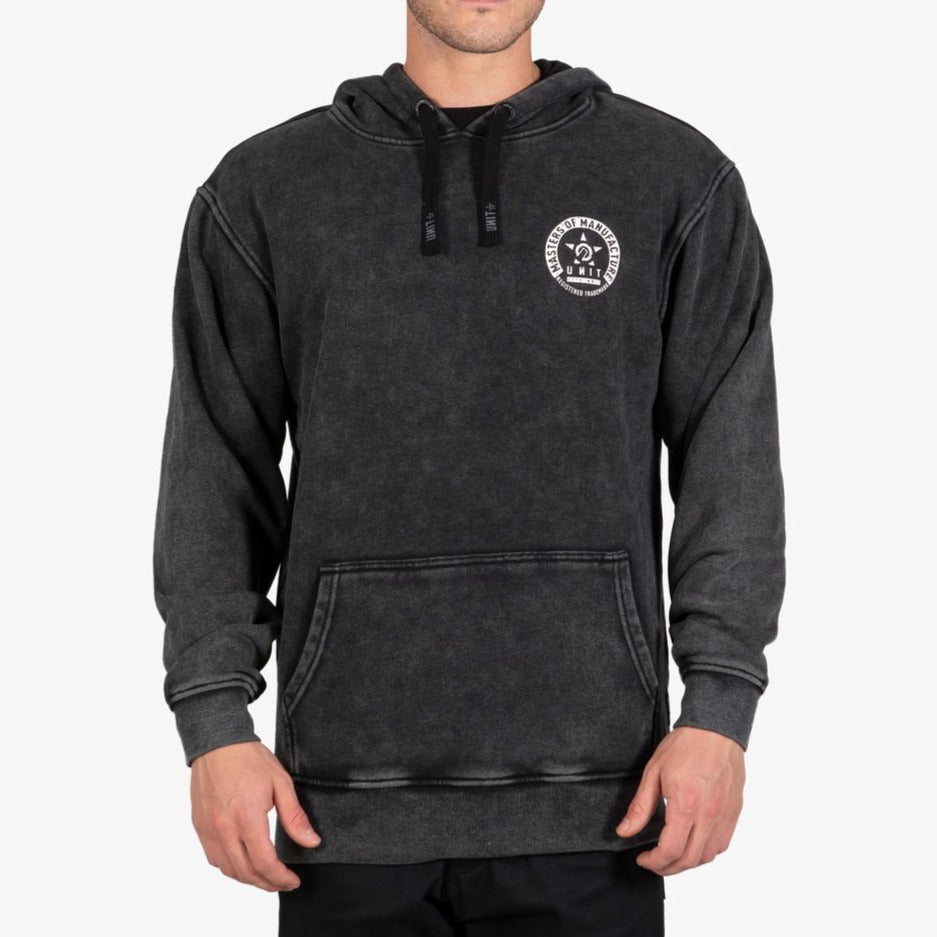 Someone stands against a plain light background wearing the UNIT Branch Fleece Hoodie: a faded black, comfortable hoodie featuring a small white circular logo on the left chest and a front pocket.
