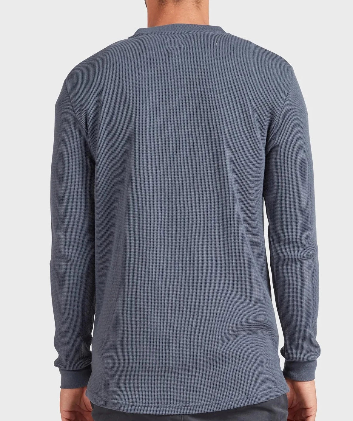 A person wearing the Academy Brand Sycamore Henley, a long-sleeve, 100% cotton shirt with a textured blue finish and subtle pattern, is shown from the back against a plain, light background.