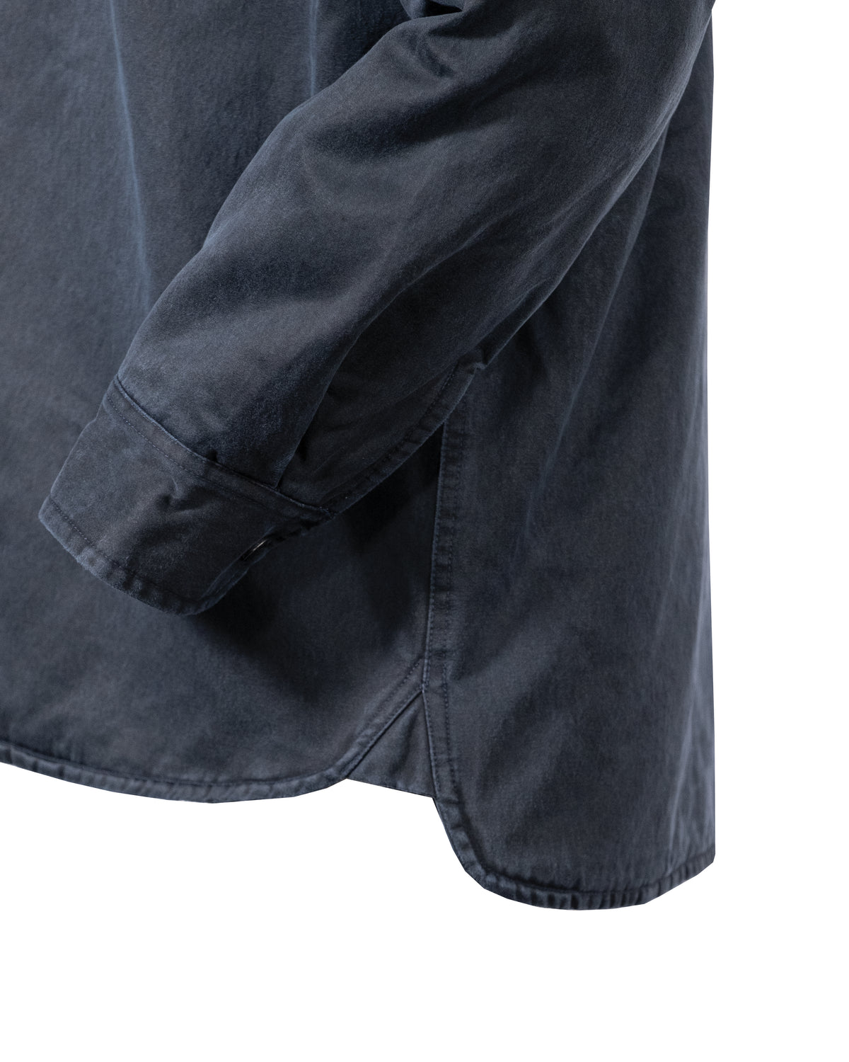 Close-up of the Outback Loxton Jacket in a dark color, highlighting the side seam and sleeve cuff. The soft fabric shows a slight hem curve, with visible stitching along the edges, resembling precise jacket craftsmanship.