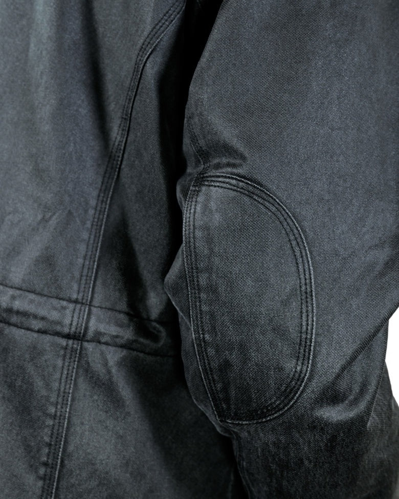 Close-up of the upper back and sleeve of the Outback Nolan Jacket, showcasing detailed stitching and texture. The image highlights the elbow area, featuring a reinforced patch with visible seams. The fabric appears sturdy and slightly faded, giving a vintage look to this hard-wearing jacket.