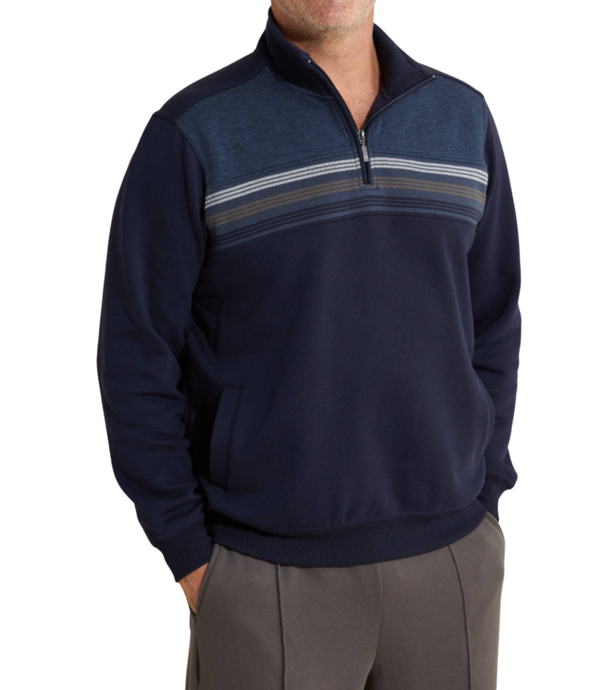 A person wearing the Breakaway Hils Snowy Mt Fleece Half Zip, a navy blue, comfortable fleece featuring horizontal stripe detailing across the chest and a half zip front. Their hands are in the pockets of the pullover. The individual is also wearing grey trousers against a plain white background.