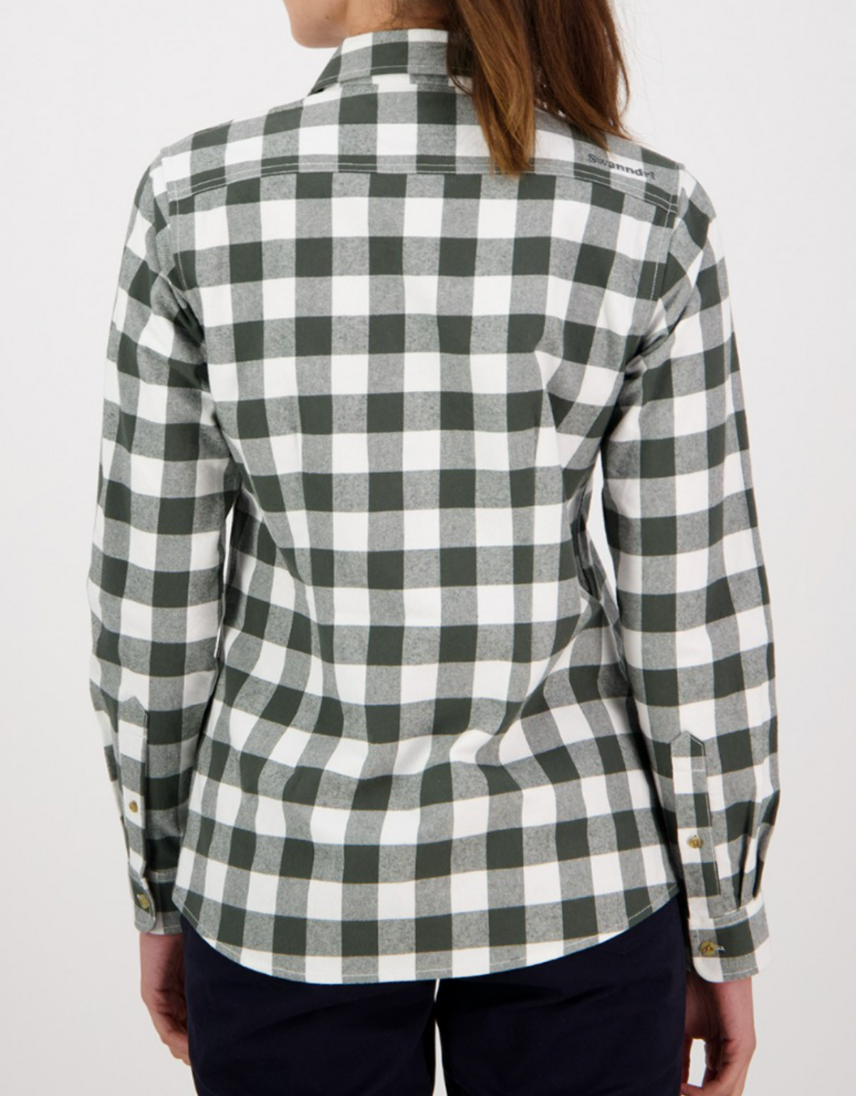 A woman with long brown hair is shown from the back, wearing the Swanndri Womens Taranaki Tailor Shirt—a stylish green and white checkered 100% cotton button-up—paired with dark pants, against a plain white background.