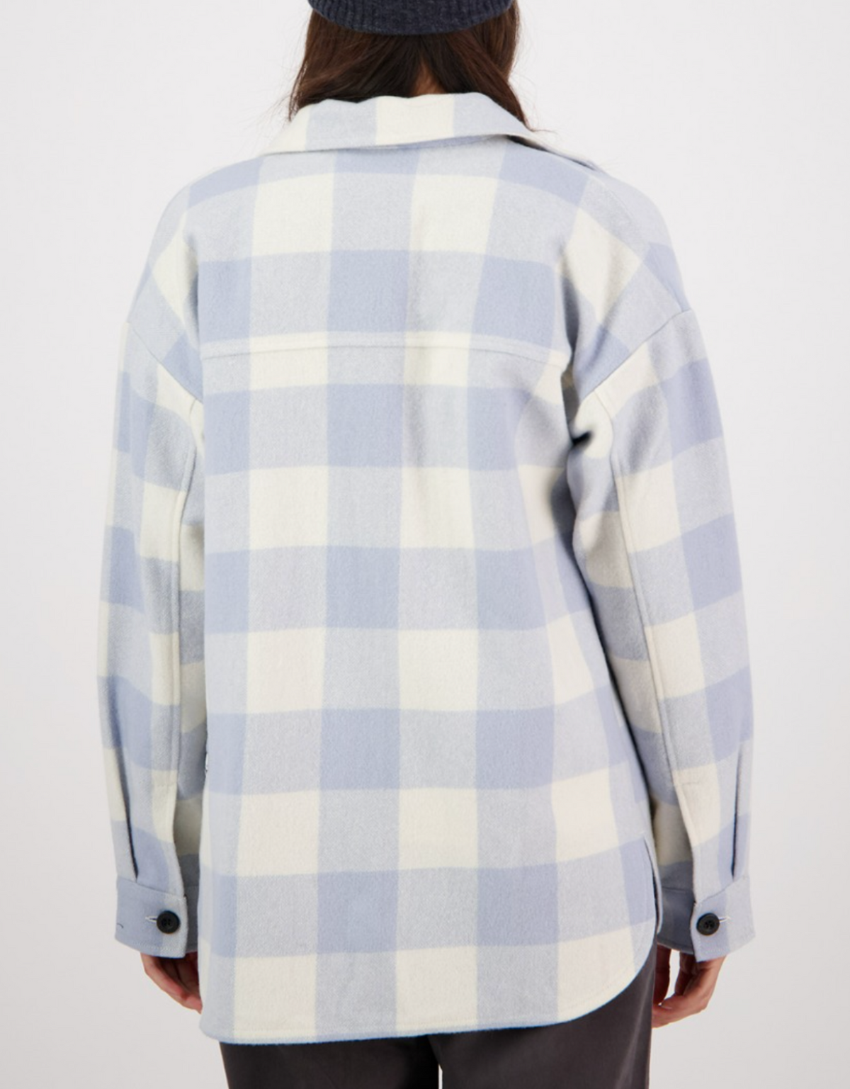 A person is shown from the back wearing a Swanndri Anchorage Wool Shirt Jacket in light blue and white check, with long sleeves and black buttons, against a plain white background.