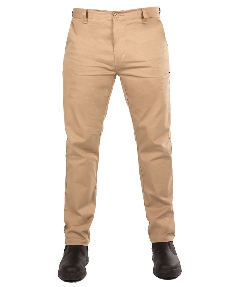 A person wearing the UNIT Ignition Stretch Pant in beige khaki. The durable work pants feature a straight-leg design and are paired with black boots. The pants have a button and zip closure, belt loops, and side pockets against a plain white background.