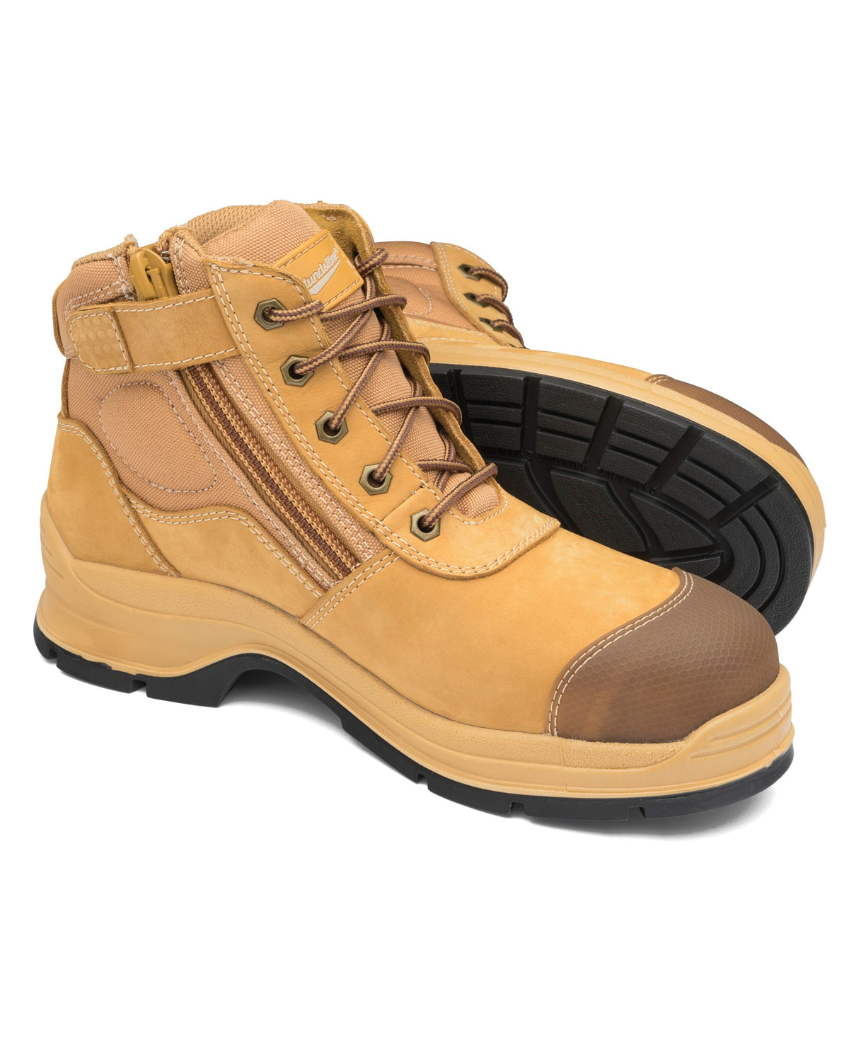 The Blundstone 318 Zip Sided Scuff Cap Safety Boot in light brown leather features black rubber soles. The design includes laces, side zippers, and a reinforced steel toe cap with SPS Max—XRD® Technology for superior comfort. One boot stands upright while the other lies on its side, showcasing the tread pattern and design details.