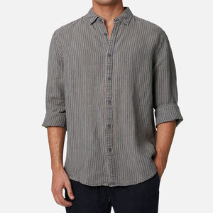 A man wearing the Industrie The Cilento L/S Shirt—a relaxed fit, long-sleeve, gray and blue striped button-up with rolled sleeves—stands against a plain light background. His head is not visible.