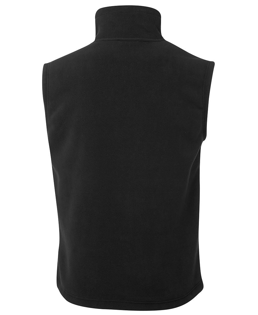 The JBs Shepherd Vest is displayed from the back, showcasing its high collar and sleeveless design with simple, clean lines in a solid black color. The fabric looks soft and warm, making it ideal for layering in cooler weather—a perfect addition to any JBs Wear collection.