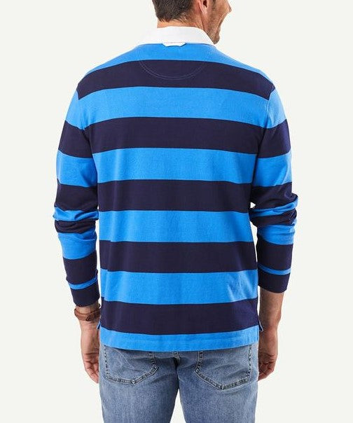 A person seen from behind is wearing a regular fit, long-sleeved Gazman Block Stripe Rugby with wide blue and navy horizontal stripes. They have short hair and are also sporting light blue jeans.