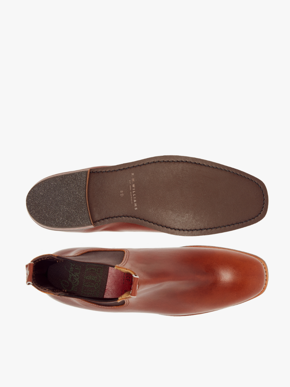 Top view of a brown full-grain leather RM Williams Erica Boot: one stands upright with sleek stitching and pull tab, the other is flipped, showing the dark brown textured heel sole. This boot epitomizes timeless style and quality craftsmanship.