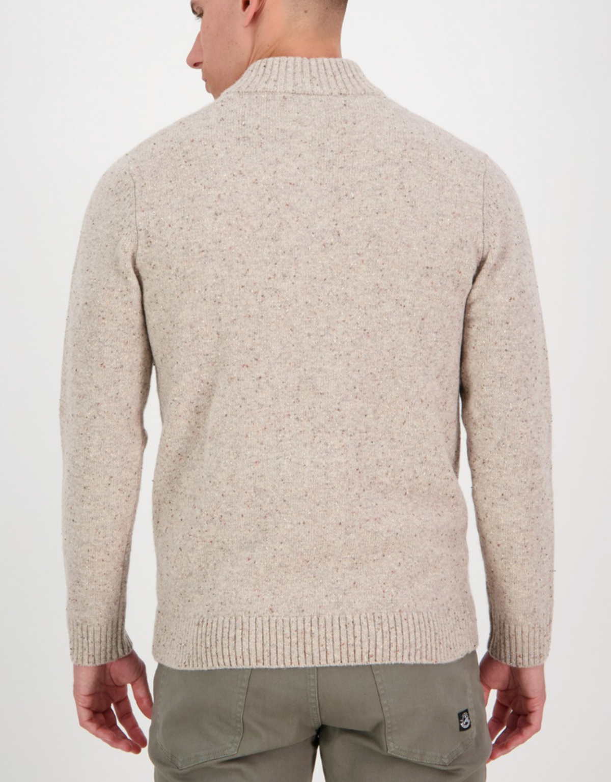A man is shown from the back wearing the Swanndri Clifton Half Placket Knit in beige speckled lambswool and olive green pants, set against a plain white background.