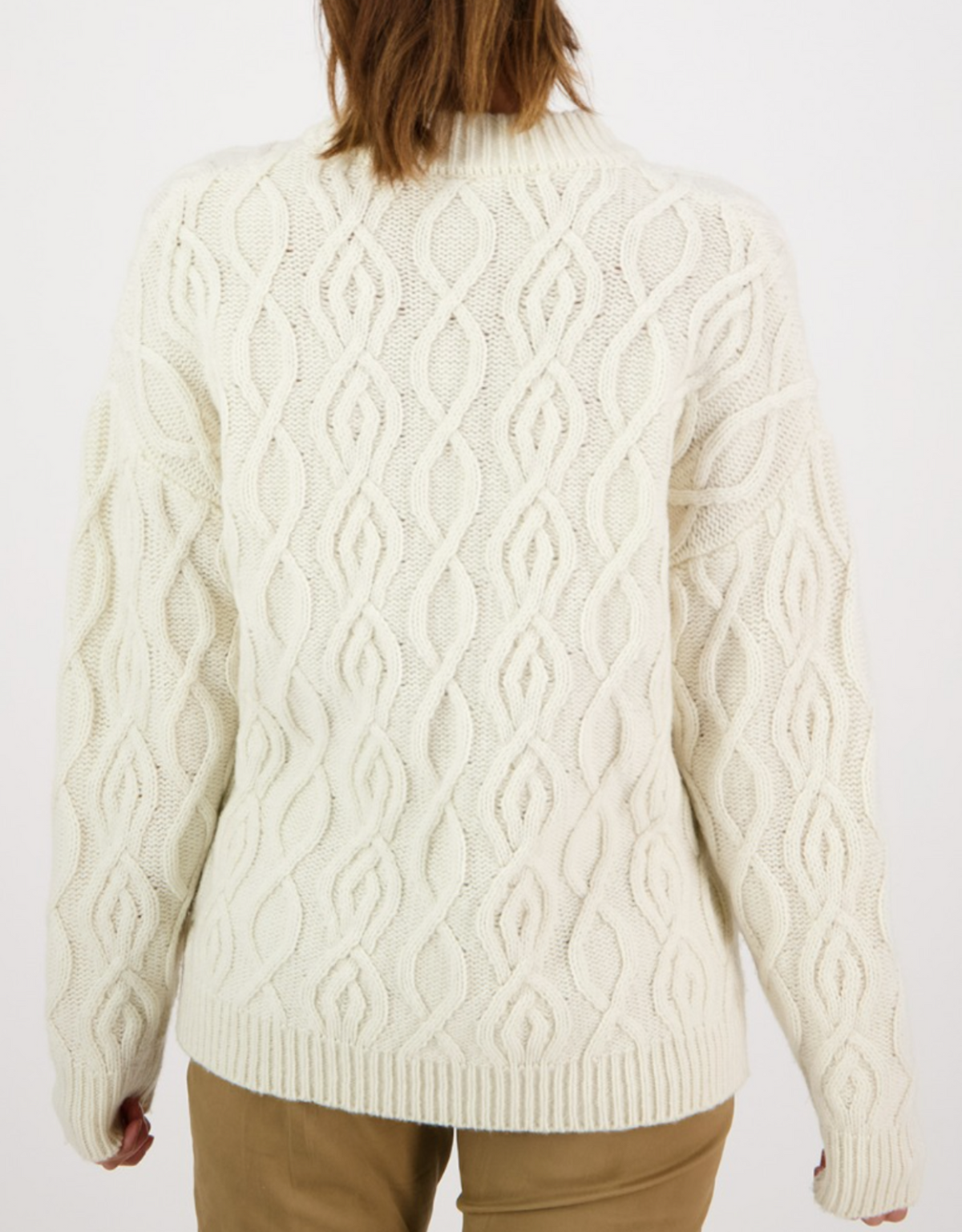 Rear view of a person wearing the Swanndri Pendeen Cable Neck Crew, a cream chunky knit lambswool jumper with a detailed braided pattern, paired with tan pants against a plain white background.