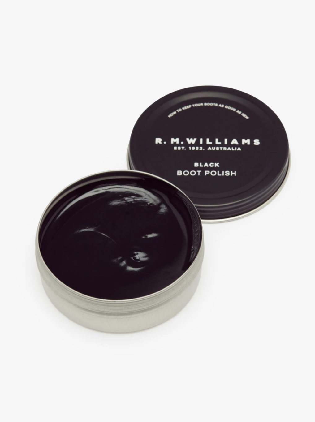An inviting open round tin container of RM Williams Stockmans Boot Polish sits ready for use. The lid, placed to the side, reads "R.M. Williams Est. 1932 - Australia, Black Boot Polish." The smooth, glossy polish promises to restore color and shine with its alcohol-free formula.