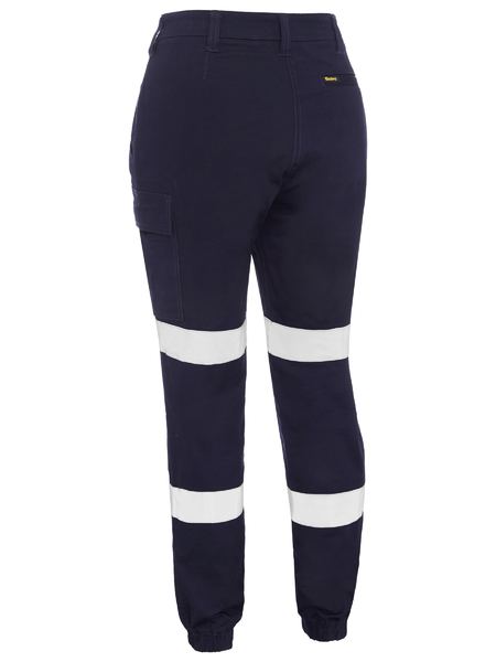The Bisley Womens Taped Cuffed Cargo Pant, in navy blue cotton, includes two white reflective bands per leg for visibility, a side cargo pocket for practicality, and elastic ankle bands for a snug fit.