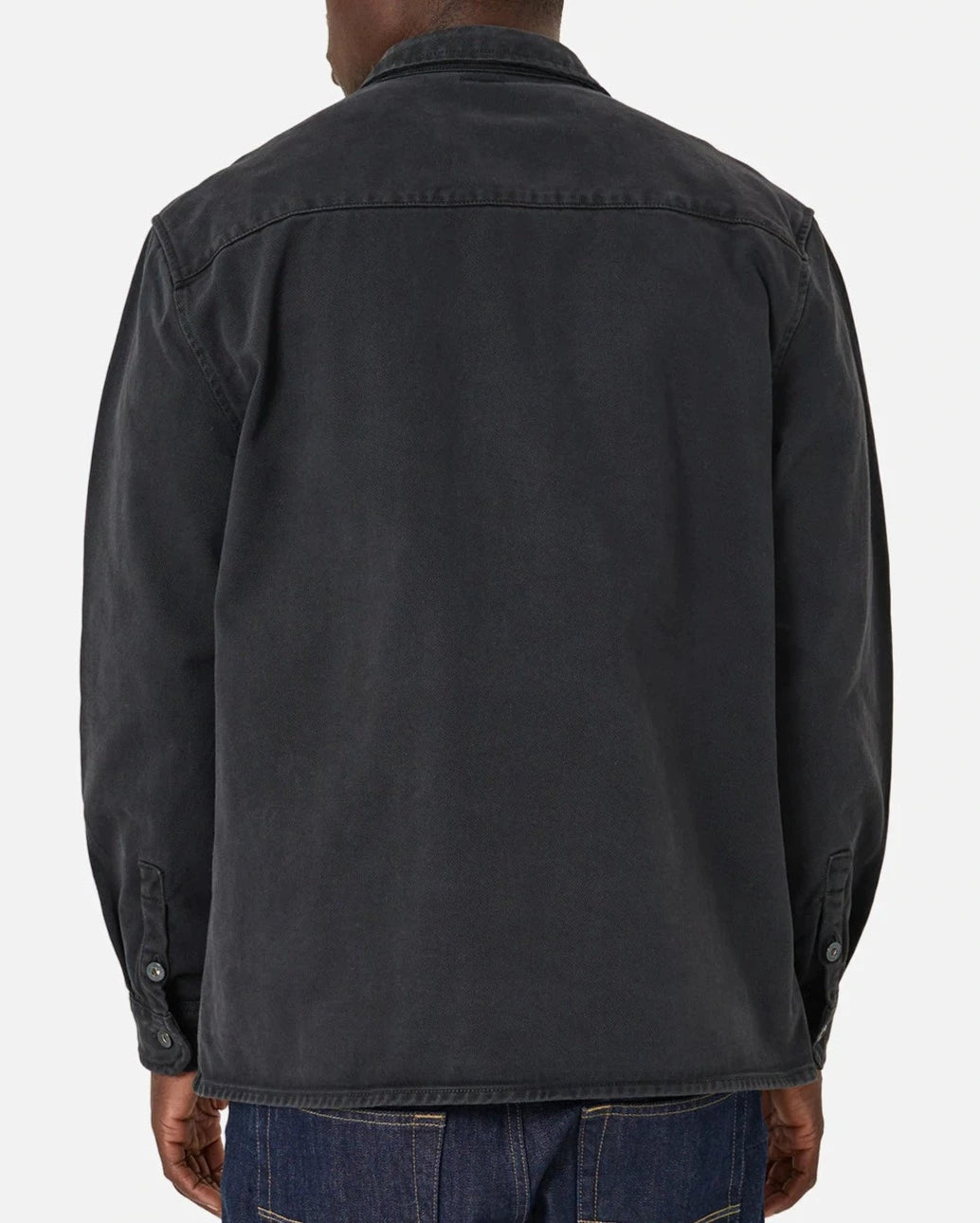 A person in the Industrie The Woodbury Shirt, a comfortable dark cotton button-up with long sleeves, and denim jeans, stands against a plain light background.
