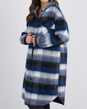 Against a simple backdrop, someone dons the Foxwood Nellie Jacket, showcasing a stylish plaid design in shades of blue, black, and white.