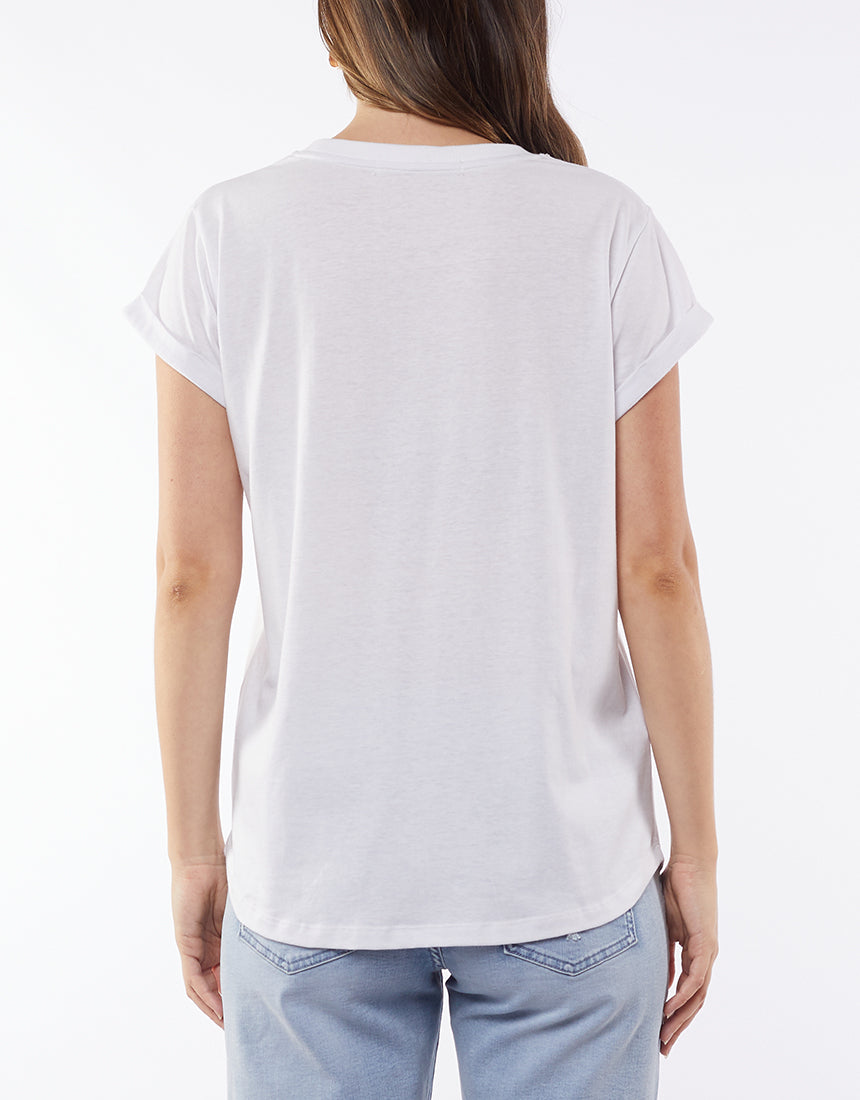 A person with long hair, back to the camera, wears a Foxwood Signature Tee known for its lightweight, breathable material. It's casually paired with light blue jeans against a plain white background, highlighting this wardrobe staple effortlessly.