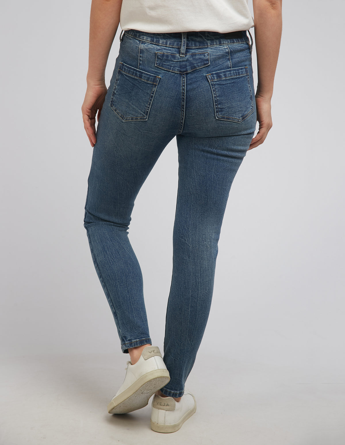 A person wearing Foxwood City Jean, made from soft cotton with a skinny leg fit and two back pockets, paired with white sneakers and standing against a neutral background.