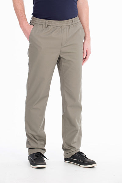 A person wearing light brown Bob Spears Pull On Pant with an elastic waistband and hands partially in pockets. The comfortable pull-on pants are paired with a dark navy shirt tucked in. The individual is also wearing black casual shoes with white soles, all set against a plain white background.
