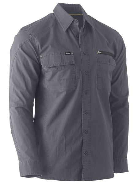 The Bisley Flex & Move Utility Work Shirt, in gray, is a long-sleeve button-up shirt equipped with two chest pockets. The left pocket features a flap and button closure, while the right pocket includes a zipper. Designed for both style and practicality, this shirt offers SPF 50+ protection and rugged durability, making it ideal for outdoor tasks.