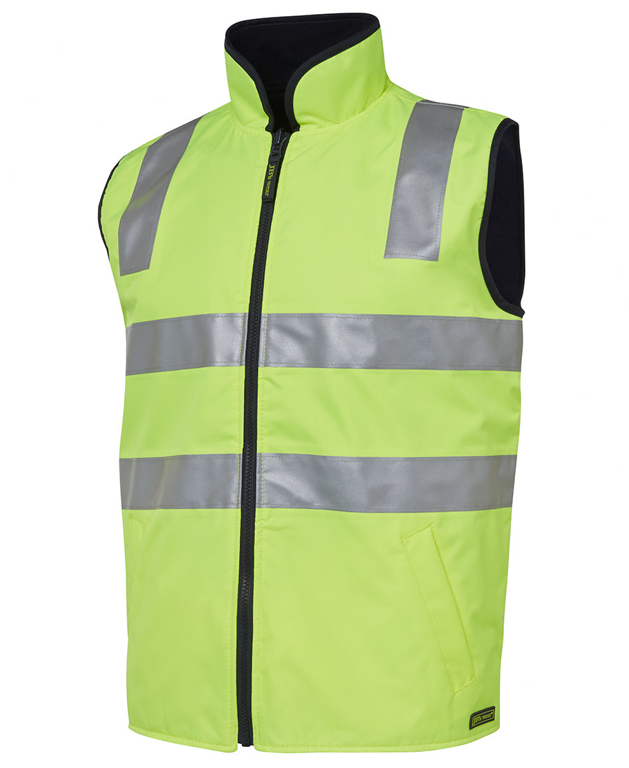 The JBs Hi Vis Reversible Vest is a neon yellow safety vest equipped with silver reflective stripes across the chest and shoulders. It features a high collar, zippered front, and side pockets, all designed to enhance visibility and safety. Its reversible design adds versatility for various work environments.