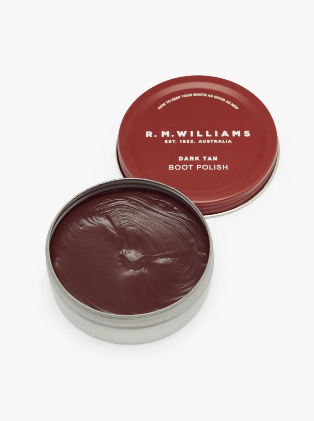 A round, open tin of RM Williams Stockmans Boot Polish in dark tan color sits invitingly. The lid, maroon with white text, reads "R.M. Williams," "Est. 1932, Australia," and "Dark Tan Boot Polish." This alcohol-free formula helps to restore color and shine to your boots effortlessly.